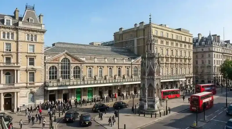 Charing Cross station and the Eleanor Cross monument on the Strand with red buses passing