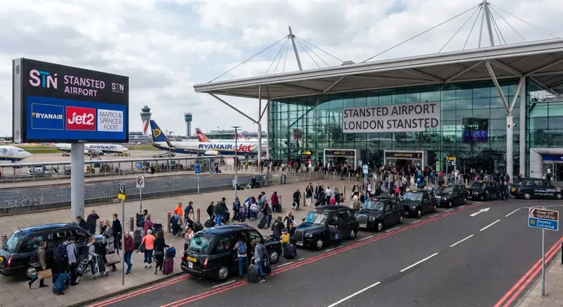 Cars and travellers on the drop-off road outside the Stansted Airport terminal